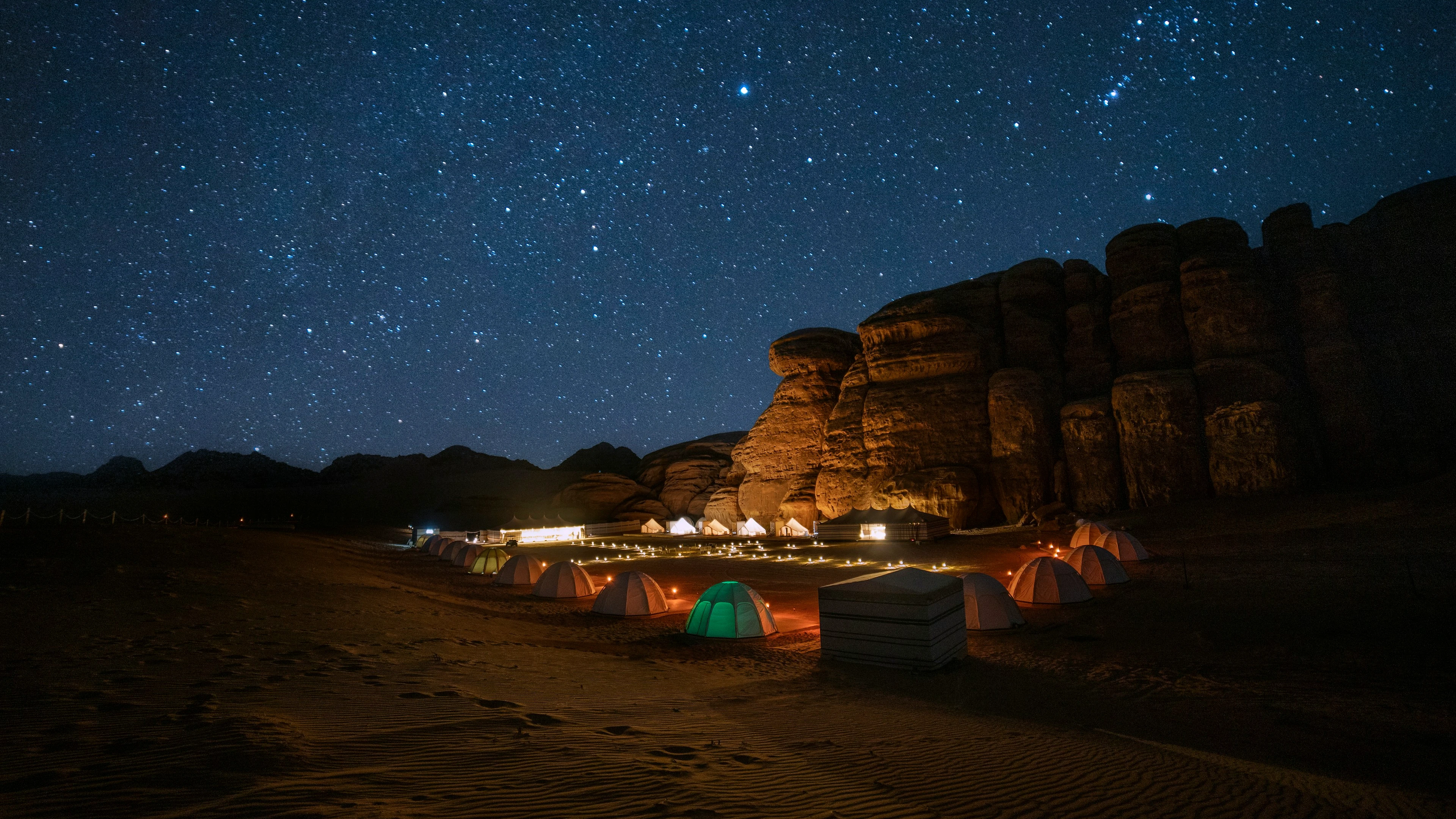 A quiet desert camp beneath a sharp night sky, with no people visible.